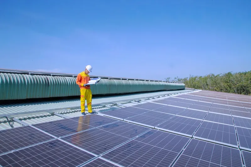 Technician inspecting a large rooftop solar array